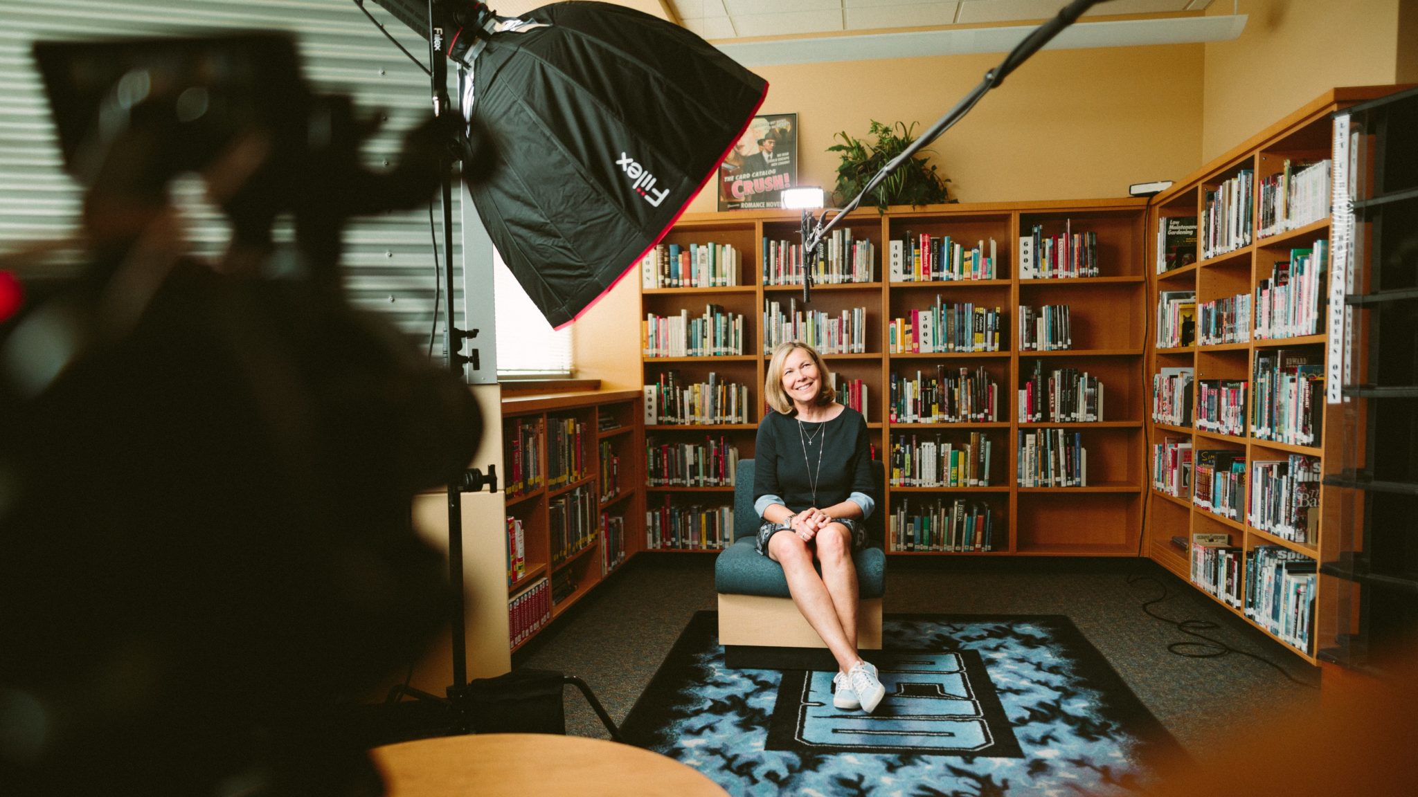 Women smiling on an interview set with a bookcase behind her